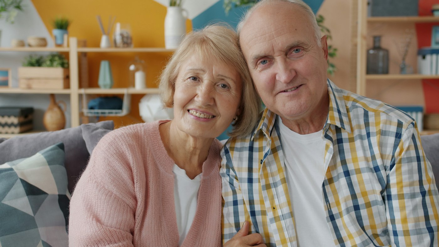 An older couple sitting close together on a sofa