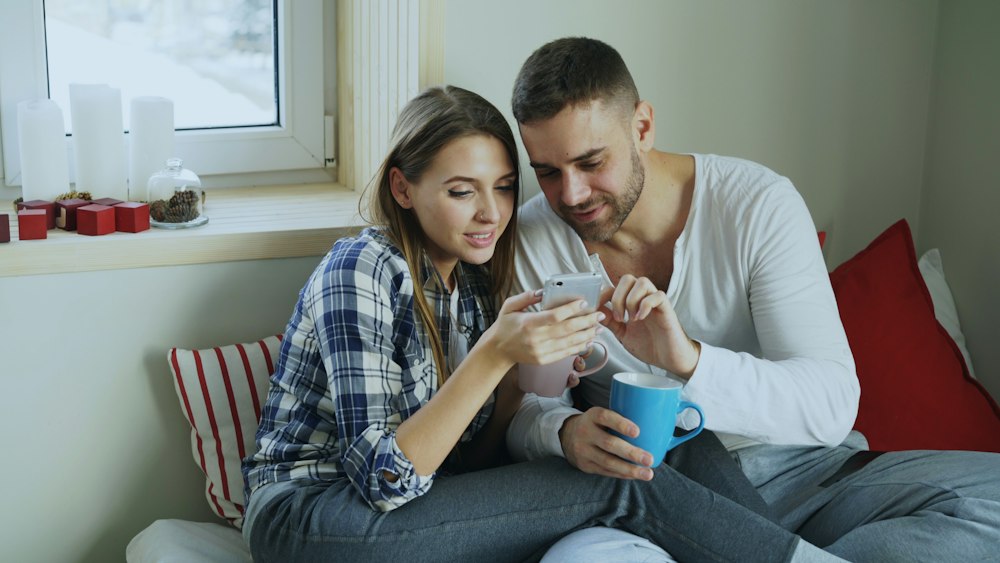 A couple looking at a phone together on a sofa